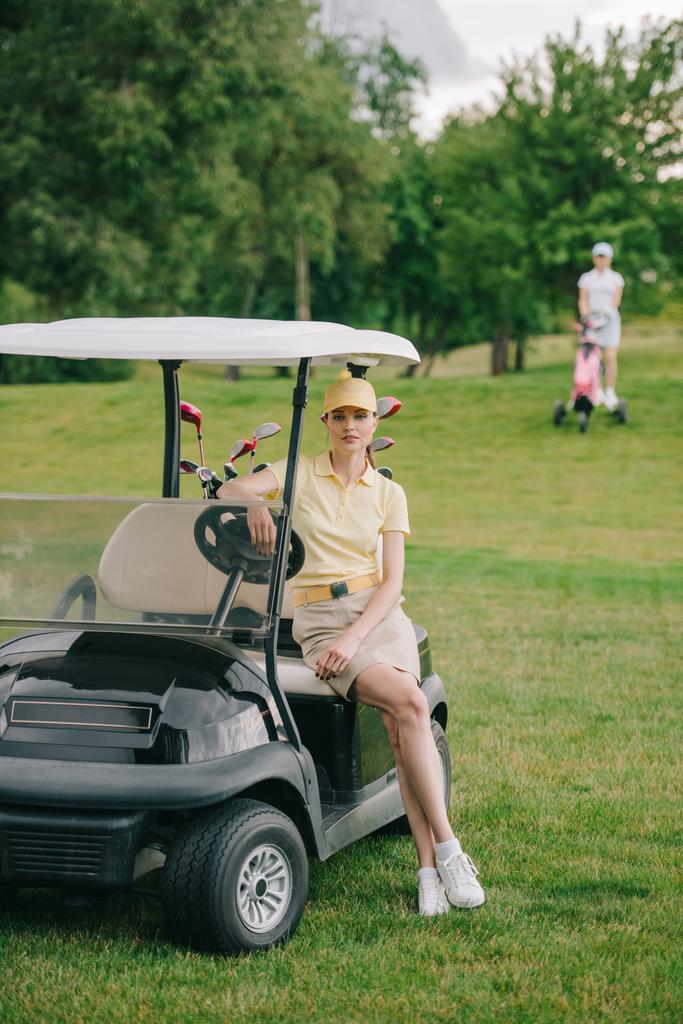 foco seletivo do jogador de golfe feminino no carrinho de golfe no gramado verde
 - Foto, Imagem
