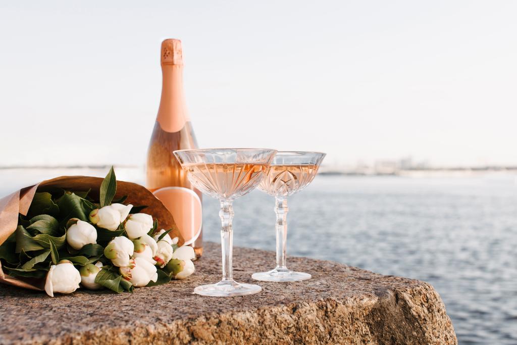 リバーサイドで堤防で 2 グラス、シャンパンのボトルと花の美しい花束のクローズ アップ ビュー - 写真・画像