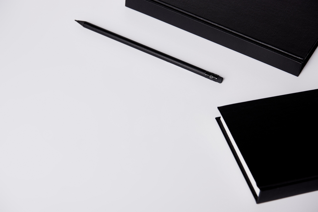 close-up shot of black hard cover notebooks with pencil on white tabletop - Photo, Image
