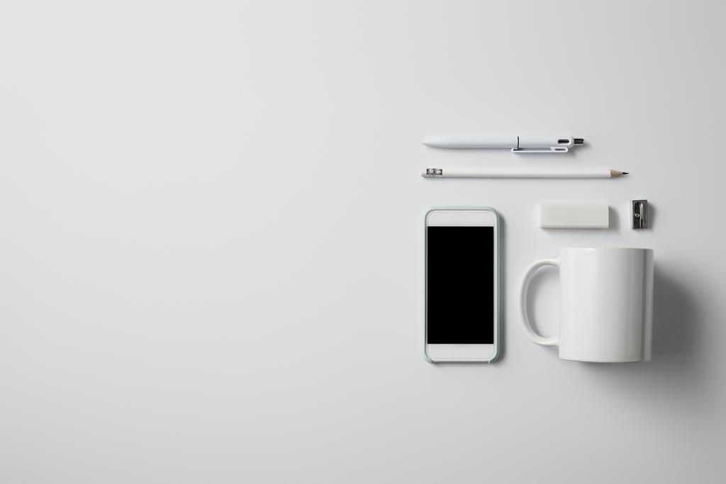 vue de dessus du smartphone avec diverses fournitures et tasse sur la surface blanche pour la maquette
 - Photo, image