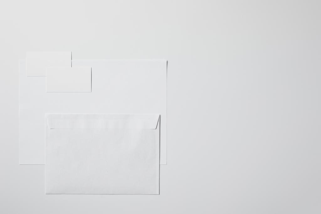 Ansicht von Blankopapier mit Umschlag und Visitenkarten auf weißer Oberfläche für Attrappe - Foto, Bild