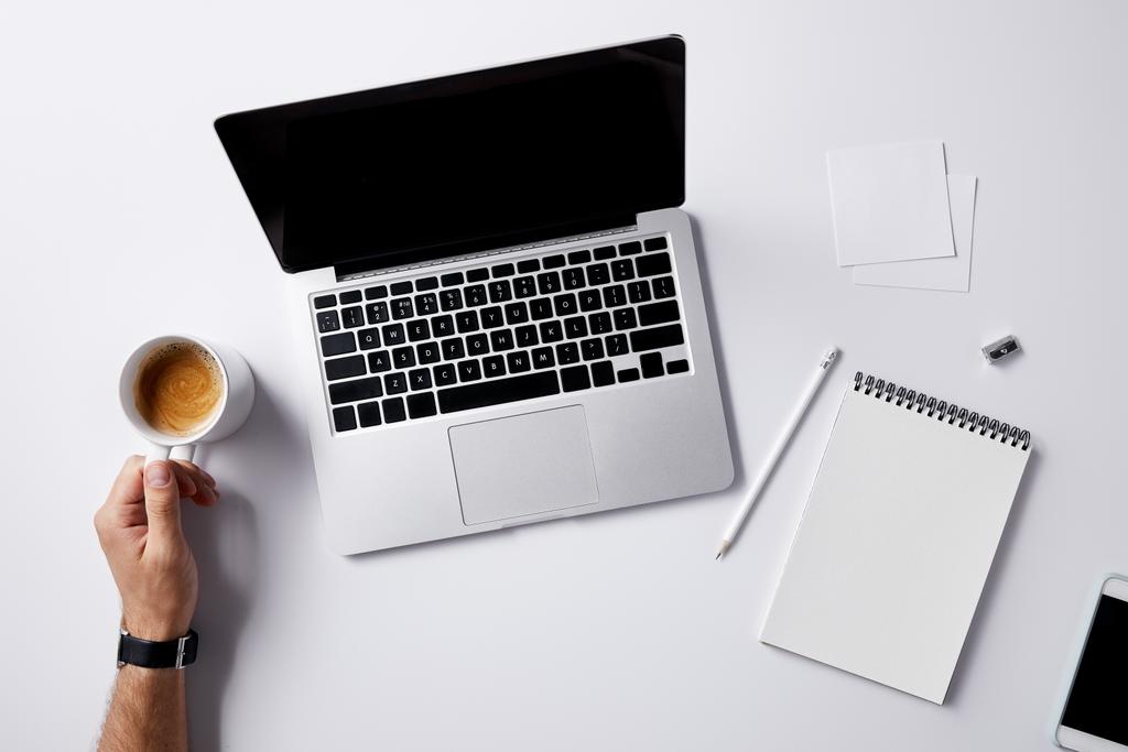 cropped shot of man folding coffee cup at workplace with supplies on white surface for mockup - Photo, Image