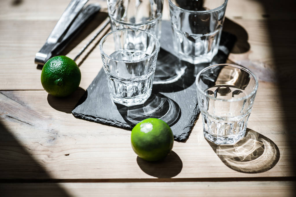 vue grand angle de verres vides, pinces et citrons verts frais sur table en bois
  - Photo, image