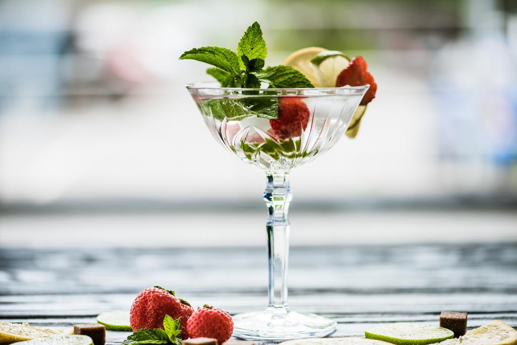 Nahaufnahme köstlicher Sommercocktail mit Minze, Limette, Zitrone und Erdbeeren im Glas - Foto, Bild