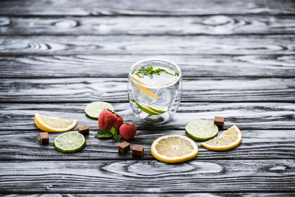 verse koude limonade in glas en rijp rijpe aardbeien op houten tafel  - Foto, afbeelding