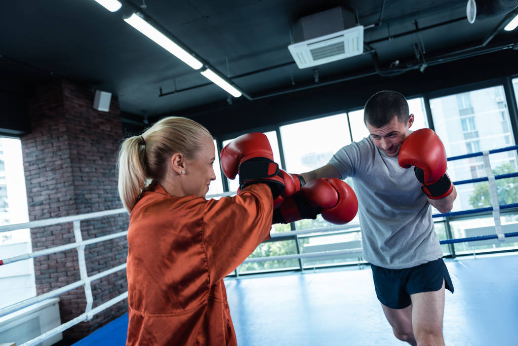 Deportista de pelo oscuro boxeando activamente con su entrenador femenino
 - Foto, Imagen