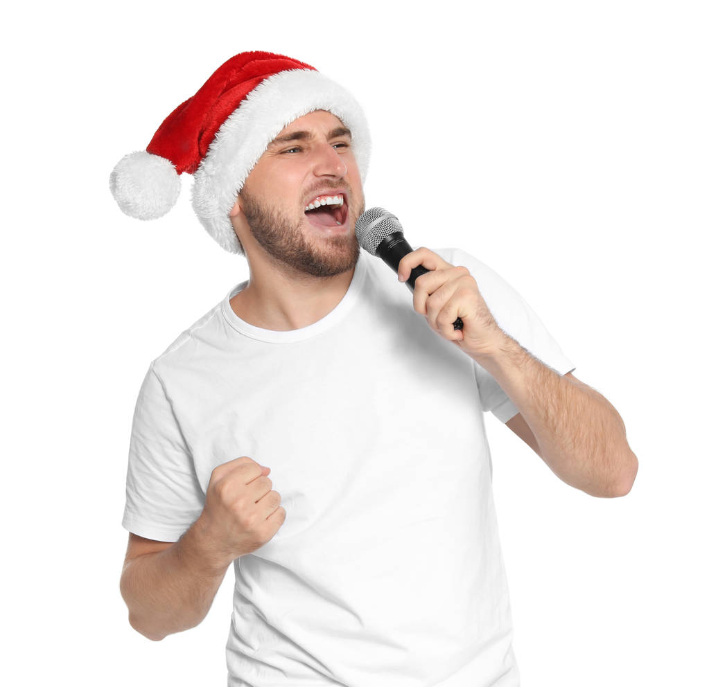 白い背景の上のマイクにサンタ帽子歌う若い男。クリスマスの音楽 - 写真・画像
