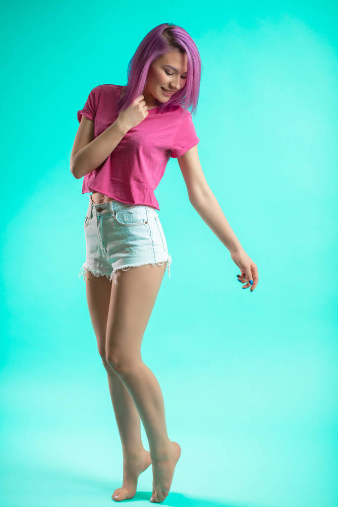 Slim fit sporty active woman in denim shorts looking at camera isolated on blue background - Photo, Image