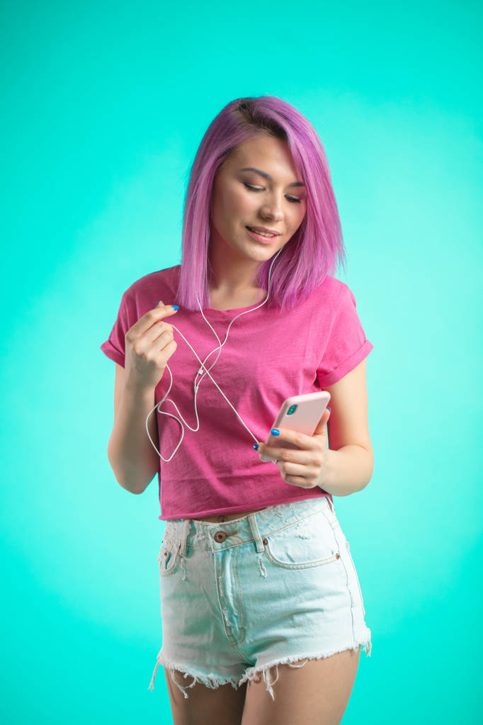 Розовая женщина слушает музыку в наушниках на синем фоне
. - Фото, изображение
