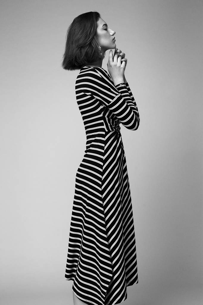 черно-белое фото великолепной молодой женщины в элегантном головном уборе, позирующей на фоне студии
   - Фото, изображение