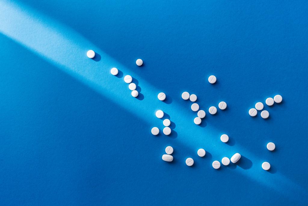 vue du dessus des pilules blanches sur fond bleu avec la lumière du soleil
 - Photo, image