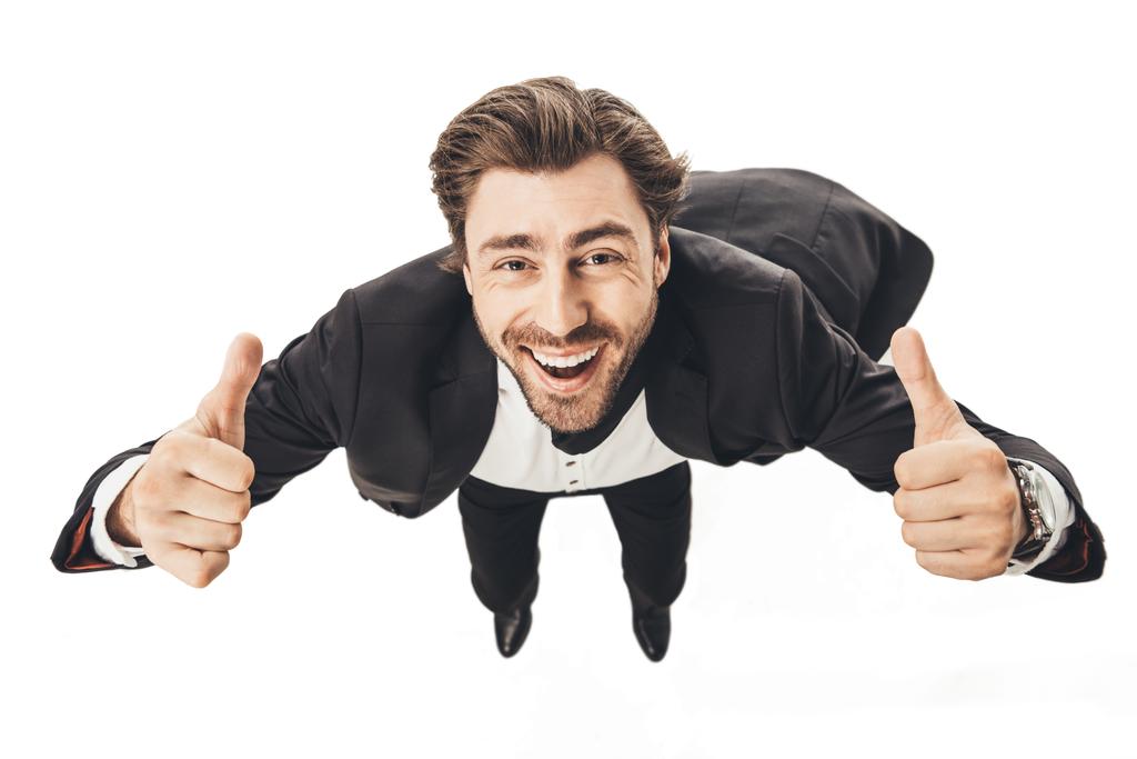Detailní záběr usměvavý mladý podnikatel pádu a ukazuje palec nahoru izolované na bílém - Fotografie, Obrázek