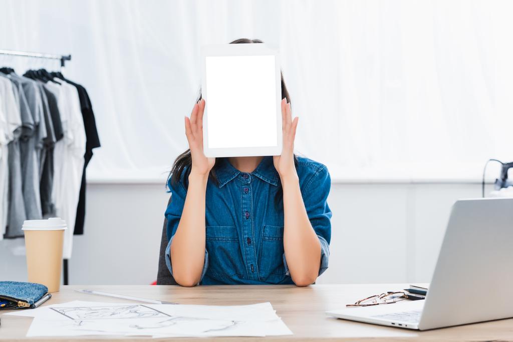 giovane donna che copre il viso da tablet digitale con schermo bianco vuoto
 - Foto, immagini