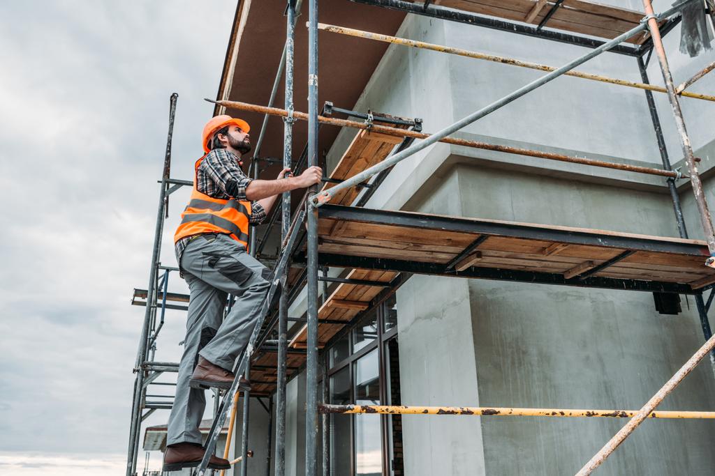 Schöner Bauarbeiter klettert auf Baugerüst - Foto, Bild