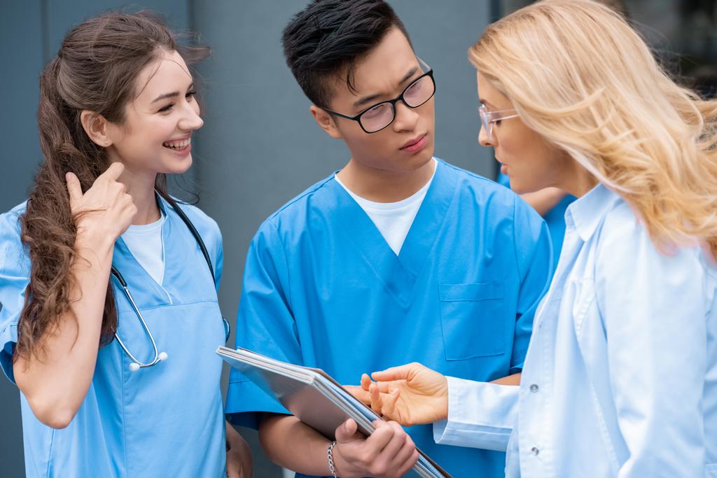 Lehrer zeigt multikulturellen Studenten an Medizin-Universität auf etwas in Notizbuch - Foto, Bild