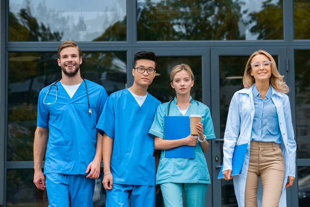 lachende leraar met multiculturele studenten lopen van medische universiteit - Foto, afbeelding