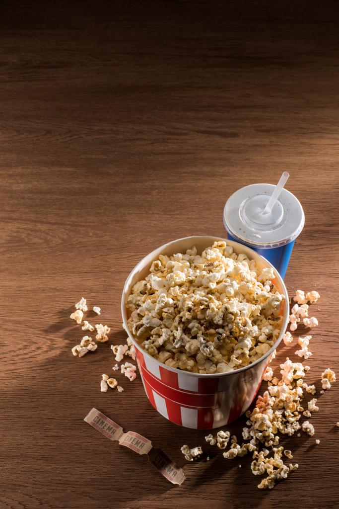 close up view of paper bucket with popcorn, soda drink and retro cinema tickets on wooden tabletop - Photo, Image