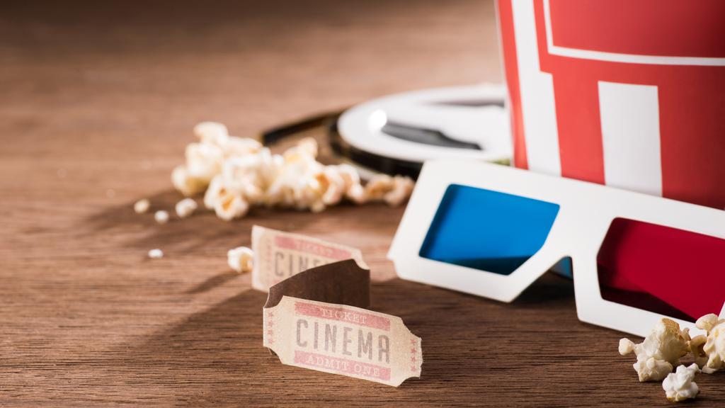 Nahaufnahme von Papiereimer mit Popcorn, Retro-Kinokarten und 3D-Gläsern auf Holztischplatte - Foto, Bild