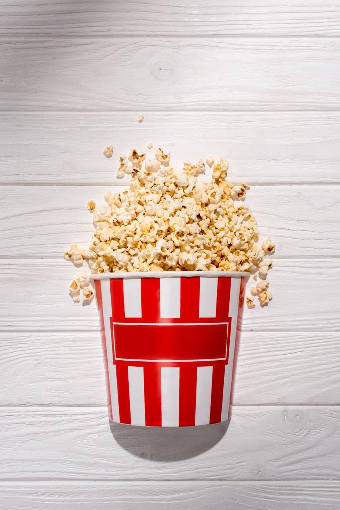 flat lay with disposable bucket with popcorn on white wooden surface - Photo, Image