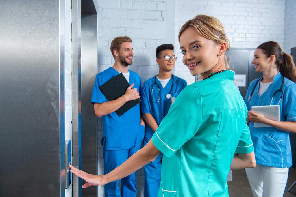 attraente studente medico premendo pulsante ascensore presso l'università medica
 - Foto, immagini