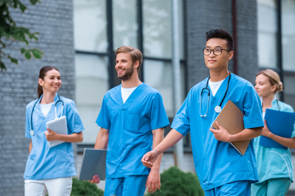 vrolijke multiculturele medische studenten lopen in de buurt van medische universiteit - Foto, afbeelding
