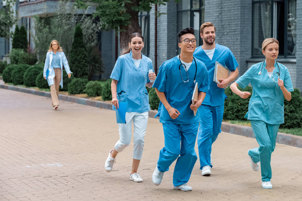 estudiantes multiculturales que corren cerca de la universidad médica
  - Foto, Imagen