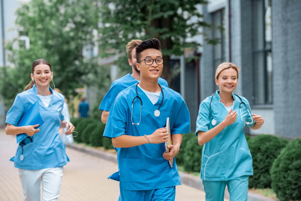 estudantes multiétnicos que correm perto da universidade médica
  - Foto, Imagem