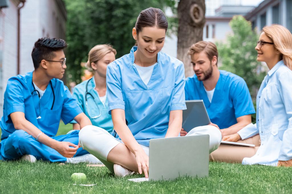 Veselá učitel a multikulturní studenti studující venku s miniaplikacemi na lékařské univerzitě - Fotografie, Obrázek