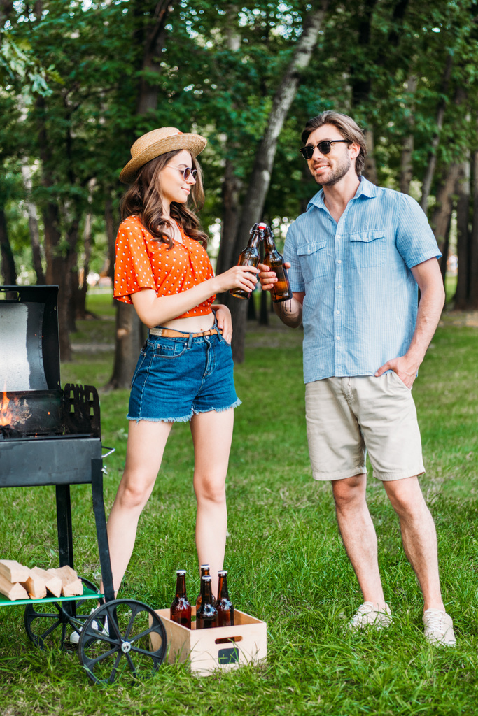 élégant couple cliquetis bouteilles de bière pendant le barbecue dans le parc
 - Photo, image