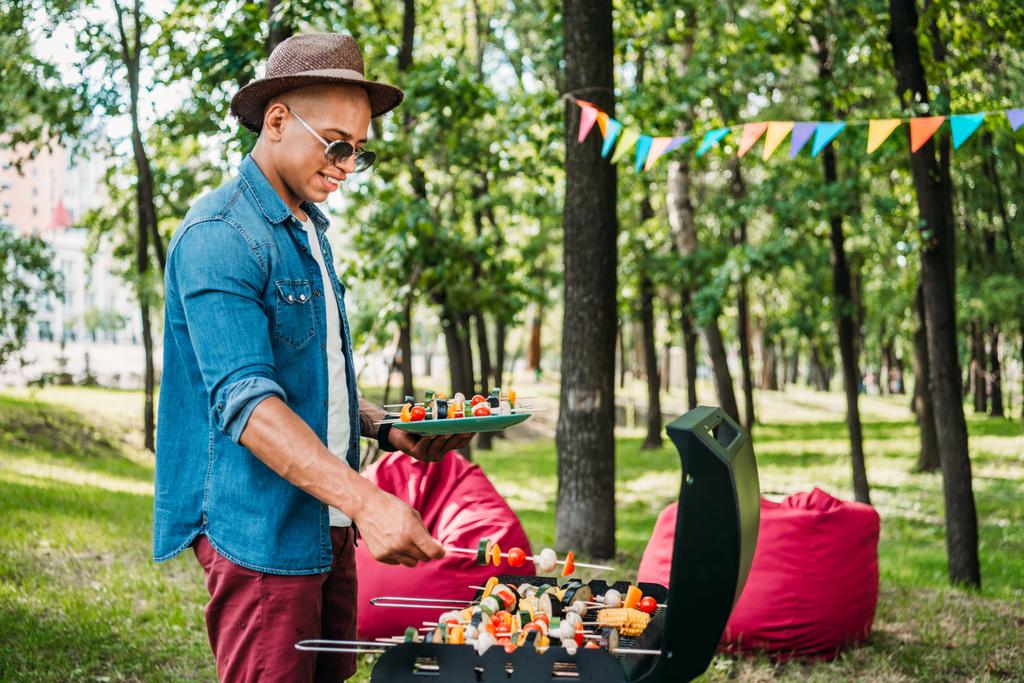 oldalnézetből a mosolygó afro-amerikai ember vesz grillezett zöldségekkel alatt grill-park - Fotó, kép