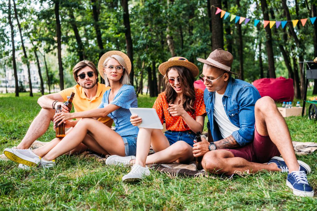 міжрасові друзі з пивом і столом відпочивають в літньому парку
 - Фото, зображення