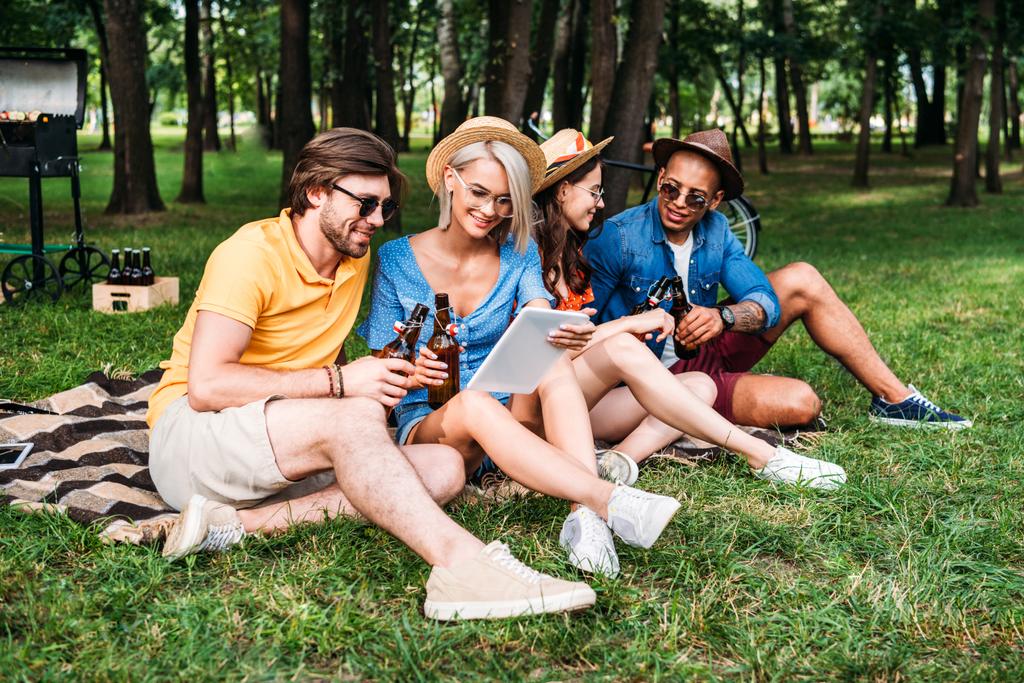 міжрасові друзі з пивом і столом відпочивають в літньому парку
 - Фото, зображення