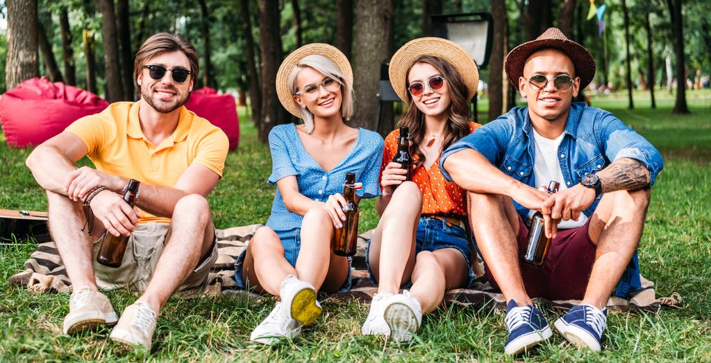 onnellisia monirotuisia ystäviä oluella lepää huopa kesäpuistossa
 - Valokuva, kuva
