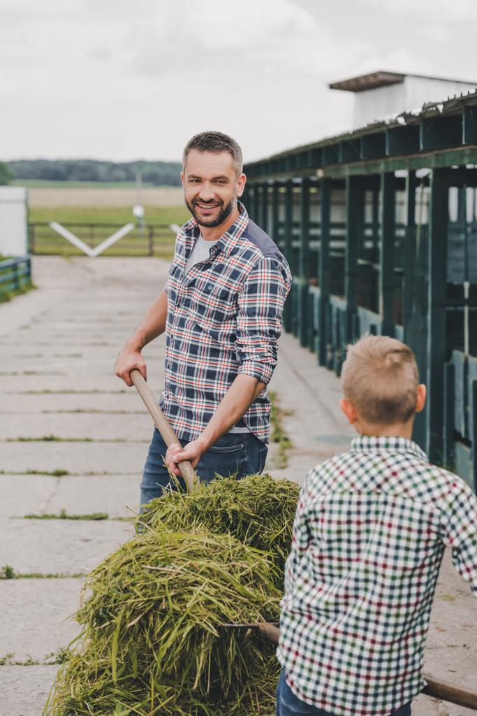 père et fils en chemises à carreaux travaillant ensemble à la ferme
 - Photo, image
