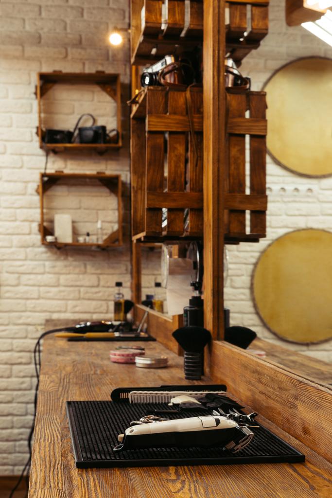 professionelle Friseurwerkzeuge auf Holzregal und Spiegel im modernen Friseursalon - Foto, Bild