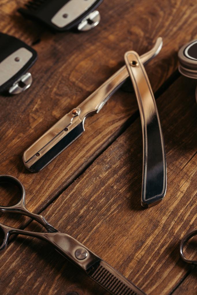 vue rapprochée du rasoir droit et des ciseaux sur la surface en bois dans le salon de coiffure
 - Photo, image