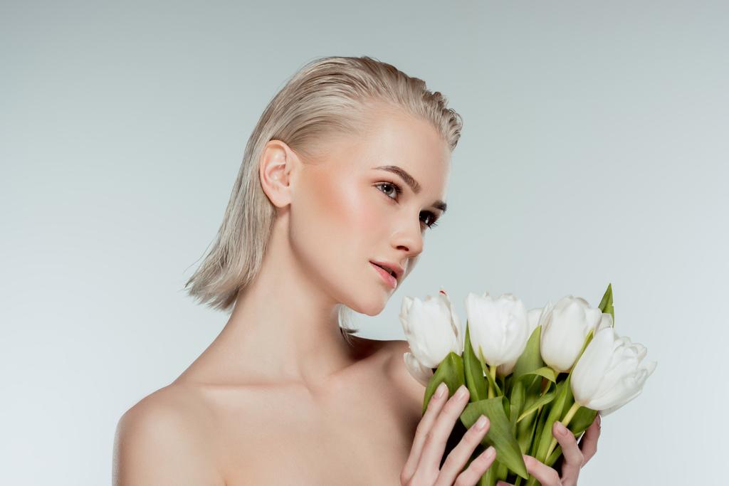 portrait of nude blonde girl posing with tulip flowers, isolated on grey - Photo, Image