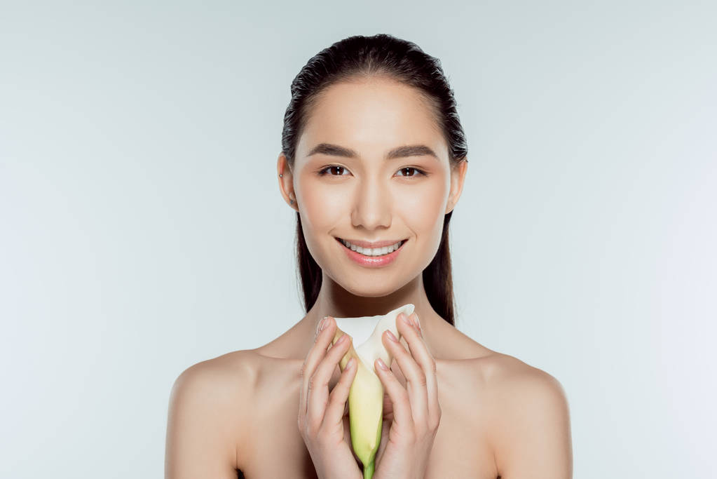 happy attractive asian girl with calla flower, isolated on grey - Photo, Image