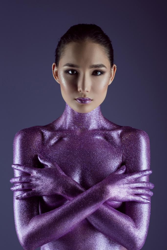 asiatisches Mädchen in ultraviolettem Glitzer, isoliert auf lila - Foto, Bild