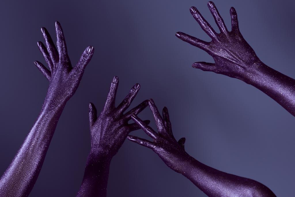 vista parcial de las manos femeninas en brillo ultravioleta, aislado en púrpura
 - Foto, imagen