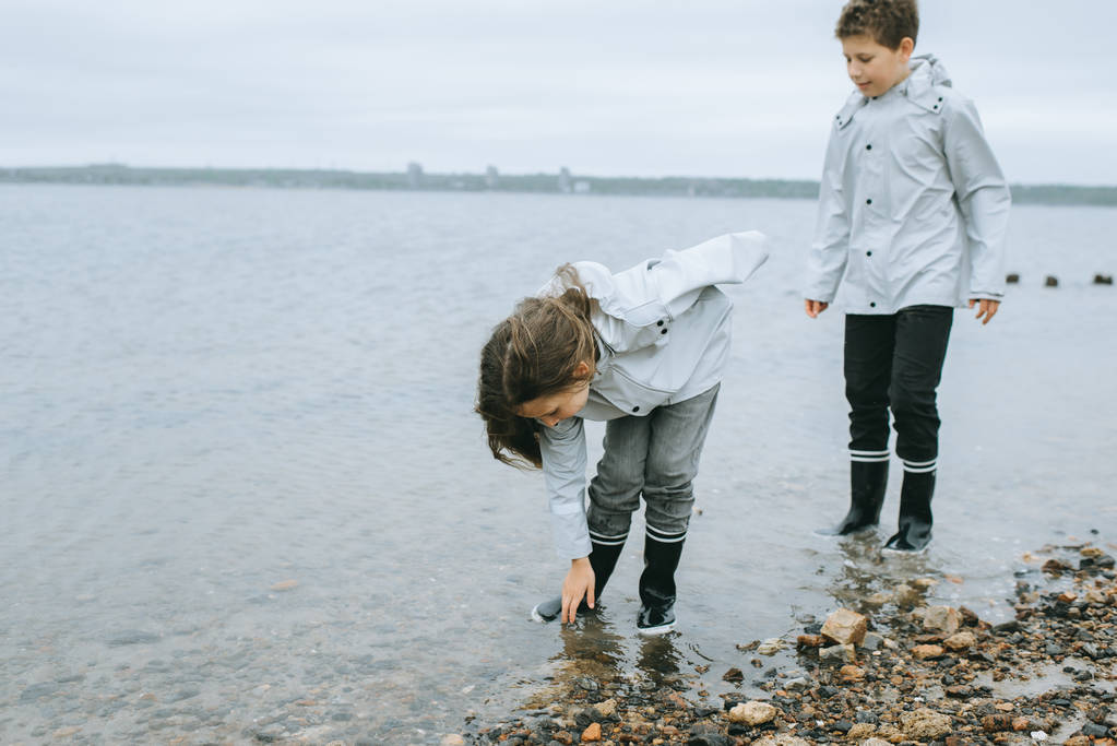 kız kardeşi ile küçük kardeşim denizin içinde yağmurluk giyen bir eğlence var - Fotoğraf, Görsel