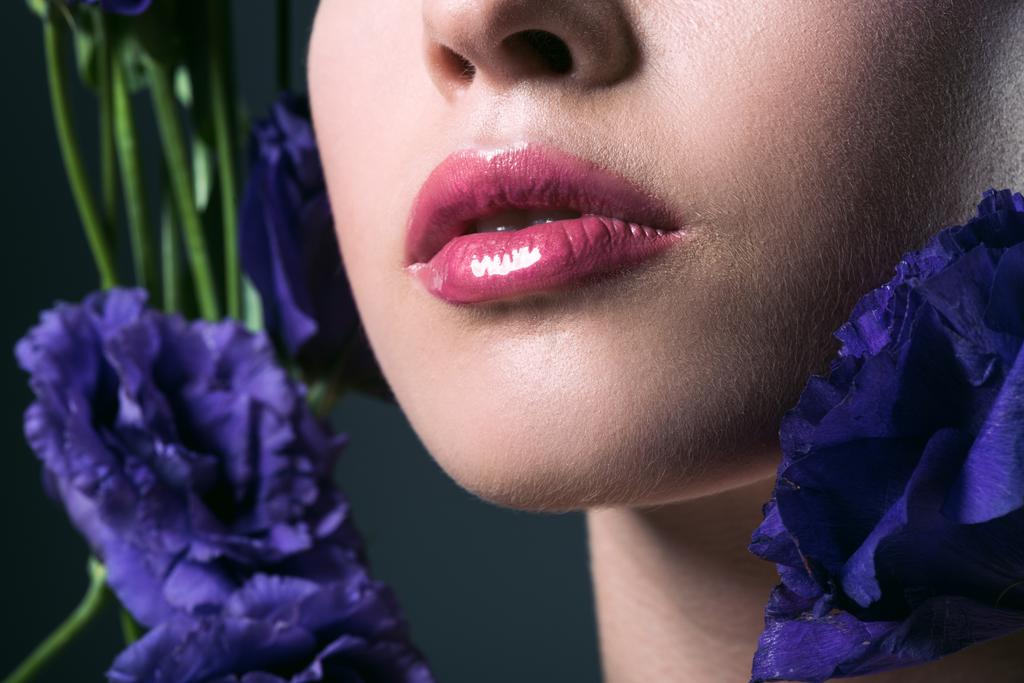 portrait partiel de belle jeune femme aux lèvres roses et fleurs d'eustomes violettes sur gris
 - Photo, image