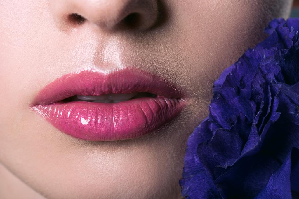 portrait partiel de belle jeune femme aux lèvres roses et fleur d'eustomie violette
 - Photo, image