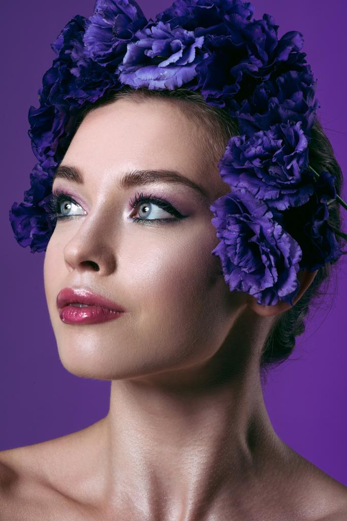 retrato de cerca de la hermosa mujer joven con flores de eustoma corona en la cabeza mirando hacia otro lado aislado en púrpura
 - Foto, imagen