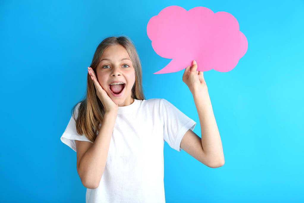 Chica joven sosteniendo la burbuja del habla sobre fondo azul
 - Foto, imagen