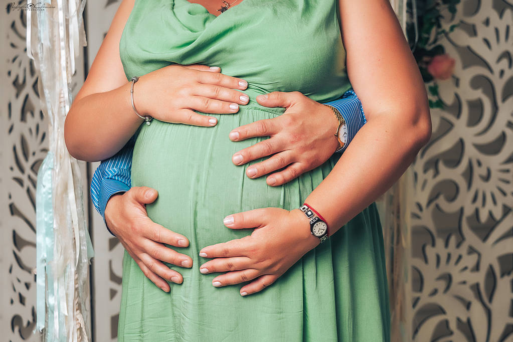 piękna kobieta w ciąży i jej przystojny mąż przytula brzuch - Zdjęcie, obraz