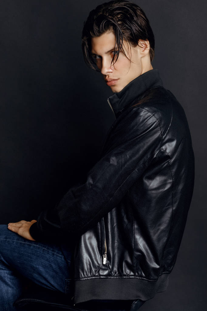 Male model in denim blue jeans and black leather jacket on black background in studio isolated - Photo, Image