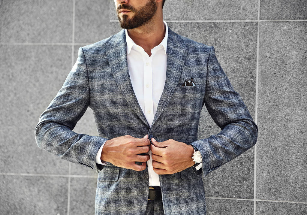 Modèle d'homme d'affaires de mode vêtu d'une élégante combinaison à carreaux posant près du mur gris sur fond de rue. Metrosexuel avec montre de luxe au poignet
 - Photo, image
