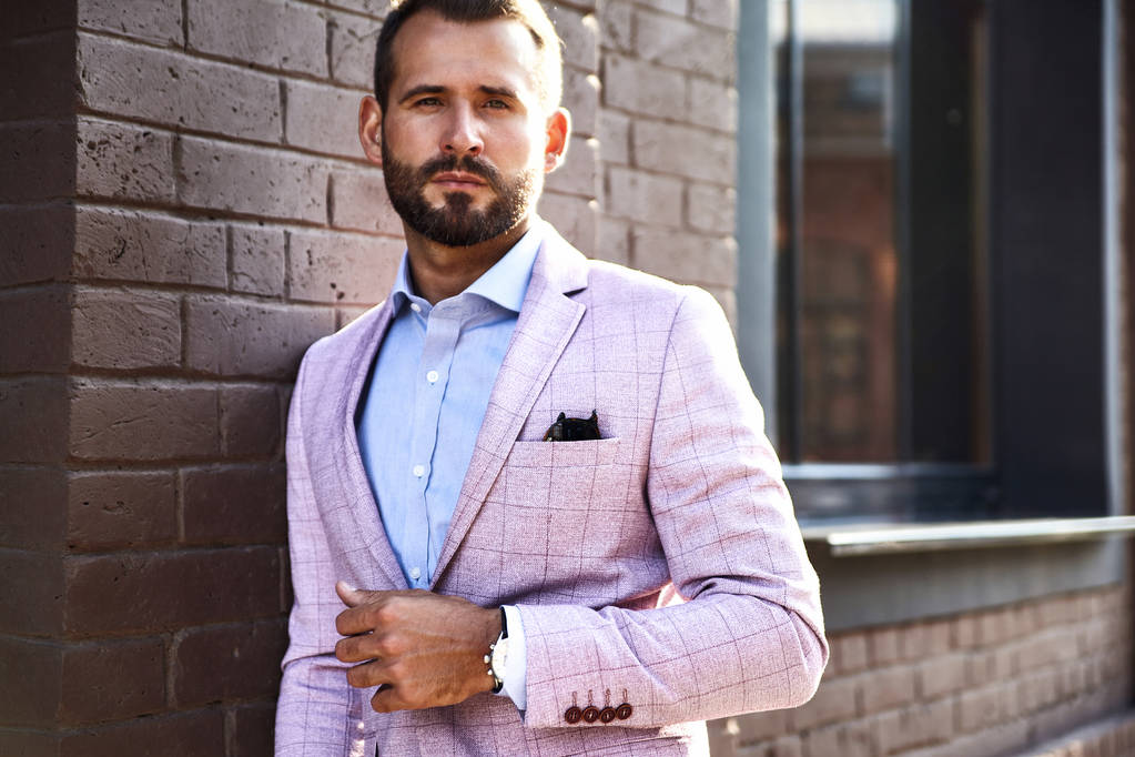 Retrato de sexy modelo de hombre de negocios de moda guapo vestido con traje elegante posando cerca de la pared de ladrillo en el fondo de la calle. Metrosexual
 - Foto, imagen