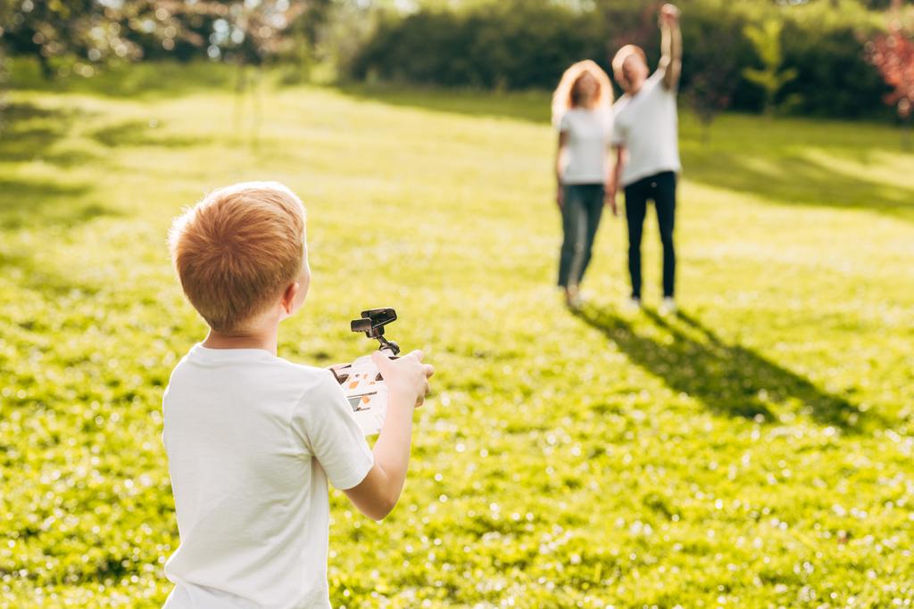 親公園で後ろに立っている間ドローンと遊ぶ少年 - 写真・画像